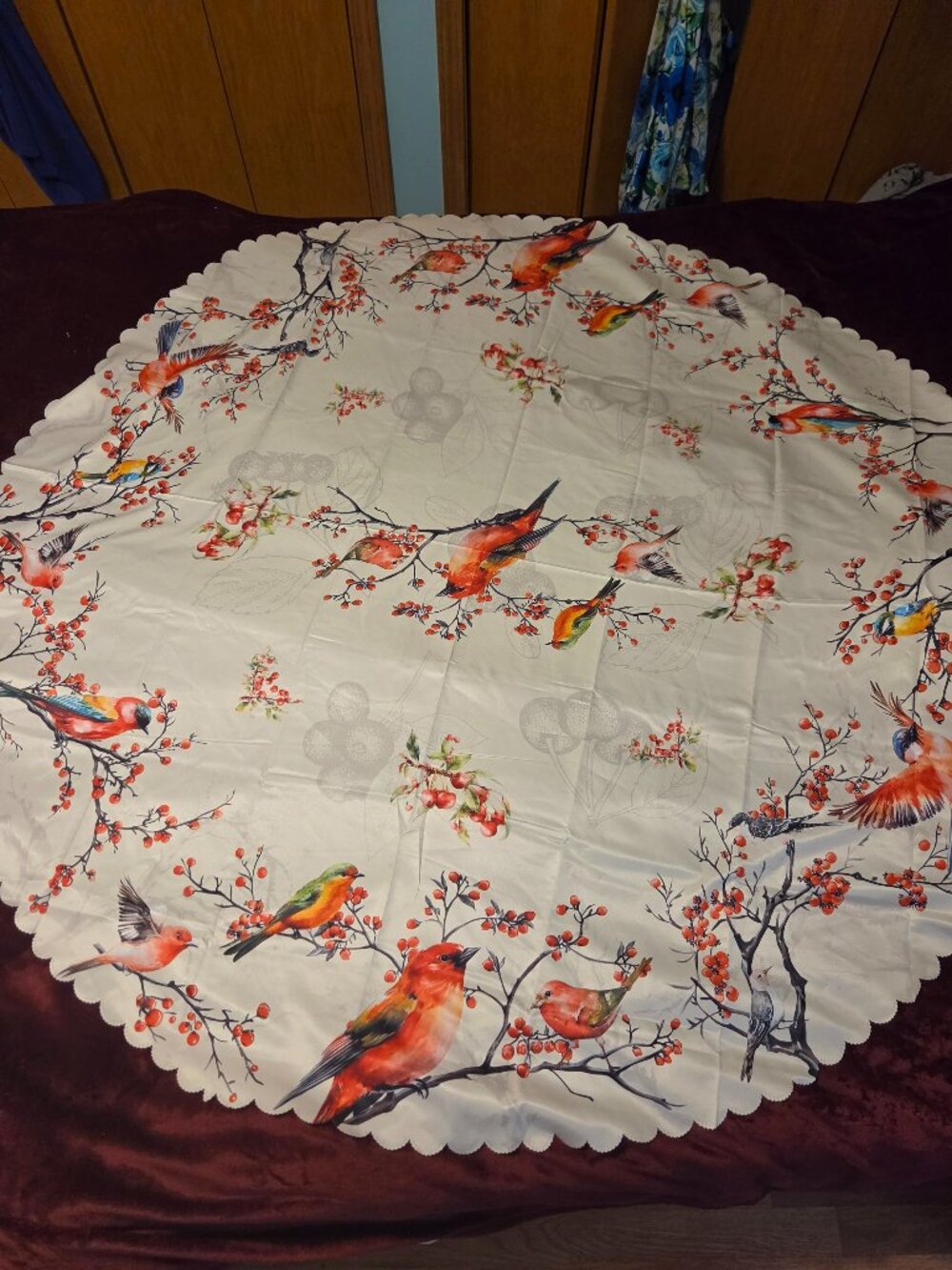 round ivory tablecloth with colorful birds perched among clusters of berries